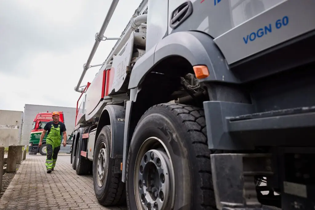 En medarbejder i sikkerhedstøj går ved siden af en stor betonpumpevogn fra Lemvig Beton.